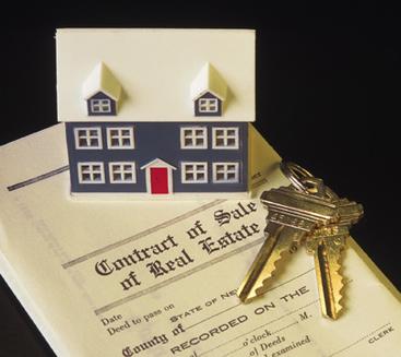 A house model and keys on top of a real estate contract.
