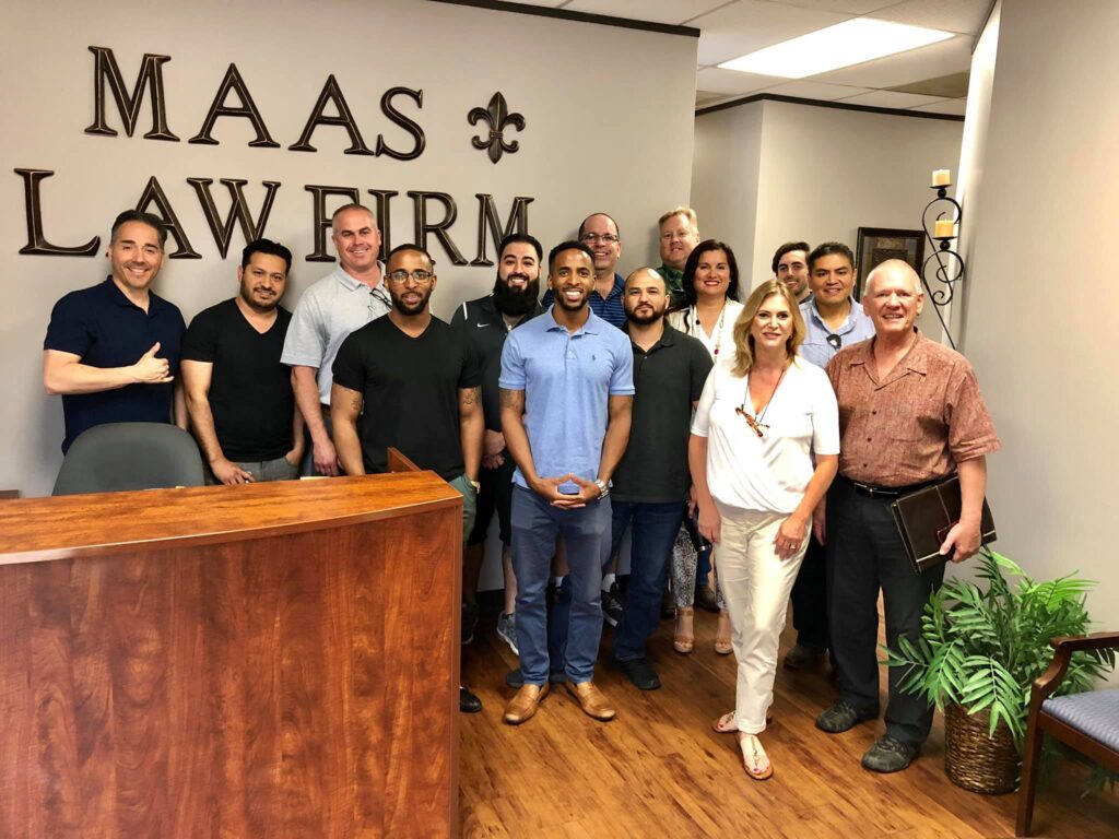 A group of people standing in front of a sign that says maas lawfirm.