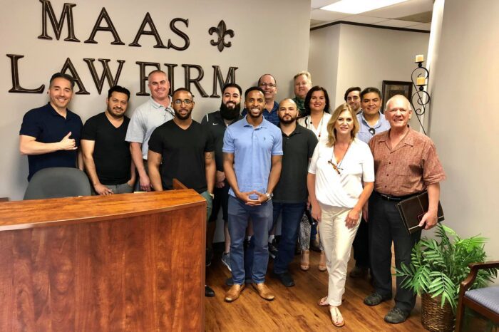 A group of people standing in front of a sign that says maas lawfirm.