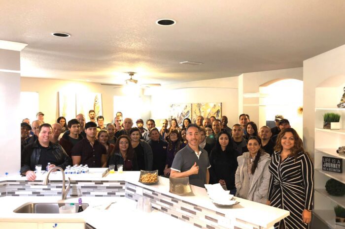 A group of people standing in a kitchen.