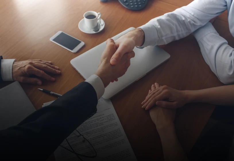 Two people shaking hands in office